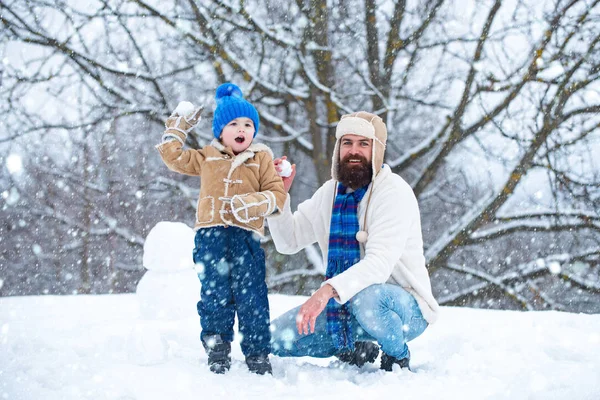 Padre e hijo juegan con bola de nieve sobre fondo blanco de invierno. Las fiestas navideñas y el invierno un nuevo año con el padre y el hijo. — Foto de Stock