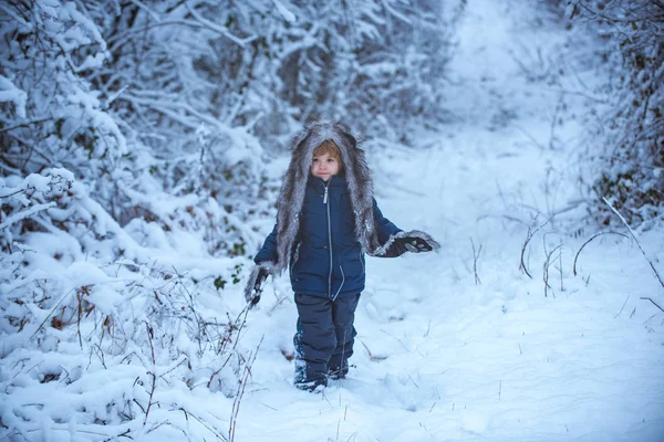 Little child in snow field. Little child boy walking in winter field. Boy dreams of winter time. Cute Winter boy in frosty winter Park.