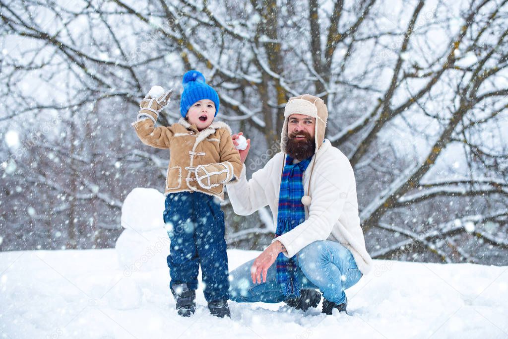 Father and son play with snowball on winter white background. Christmas holidays and winter new year with father and son.