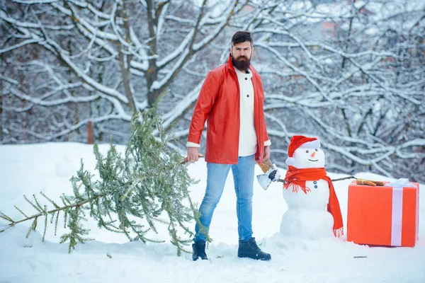 Père Noël avec sapin de Noël. Joyeux hiver. L'homme barbu porte un sapin de Noël dans le bois. Hipster bûcheron avec arbre de Noël . — Photo