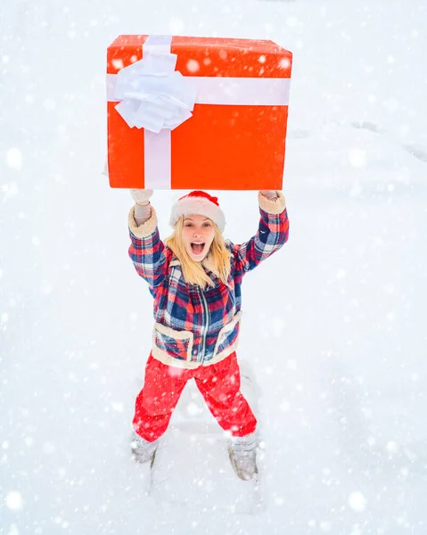 Femme de Noël tenant une énorme boîte-cadeau - pleine longueur. Noël hiver gens. Amour hiver. Femme heureuse en robe rouge s'amusant avec une grande boîte cadeau isolée sur un fond de neige blanche . — Photo