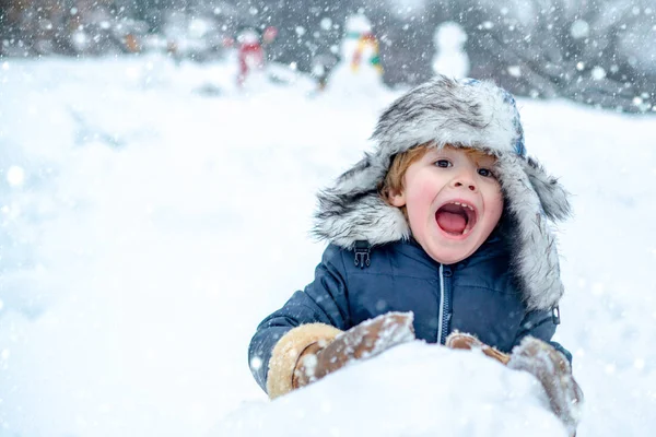 Enfant excité jouant avec la neige dans le parc sur fond de neige blanche. Enfants d'hiver dans le parc hivernal givré. Enfant mignon portrait d'hiver. Bonhomme de neige et drôle petit garçon enfant dans la neige. — Photo