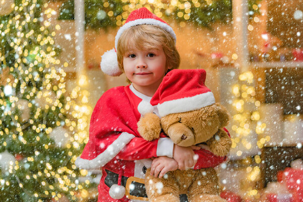 Lovely baby enjoy christmas. Funny little Santa Claus with Teddy bear toy. Dreamy toddler on Christmas eve.