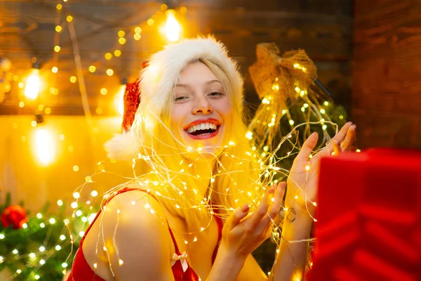 Sexy Santa mulher posando no fundo de madeira vintage. Fundo da noite com um sparkler. Preparação de Natal - menina sensual que celebra o Ano Novo. Efeito de luz piscando mágico. — Fotografia de Stock