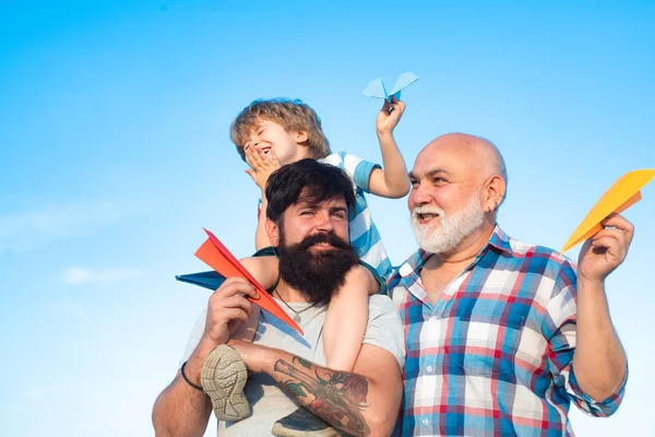 Le père qui ramène son fils au parc. Concept de génération. Mignon fils avec papa jouant en plein air. Portrait de père heureux donnant fils balade sur ses épaules et levant les yeux . — Photo