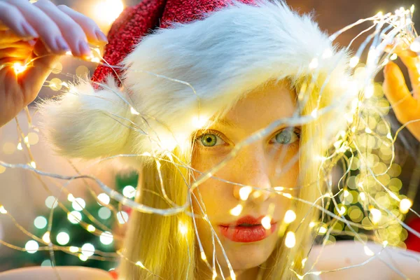 Kırmızı dudaklı, gülümseyen Noel kızı. Noel ışığı. Kız Noel Baba şapkası takıyor. Tatil kavramı. Noel havası. Kış tatili Seksi.. — Stok fotoğraf