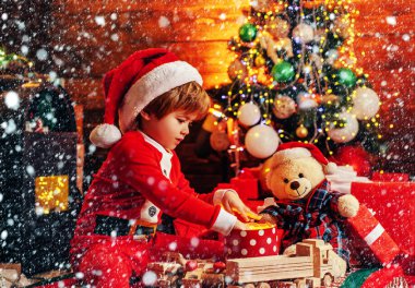 Noel çocuk hikaye kavramı. Çocukluğun ilk hatırası. Noel mucizesi ve yeni yıl duyguları. Sıcak giysiler içinde küçük bir çocuk oturan ve ahşap oyuncaklar hediye ile oynarken. Açık Uçlu Oyunlar.