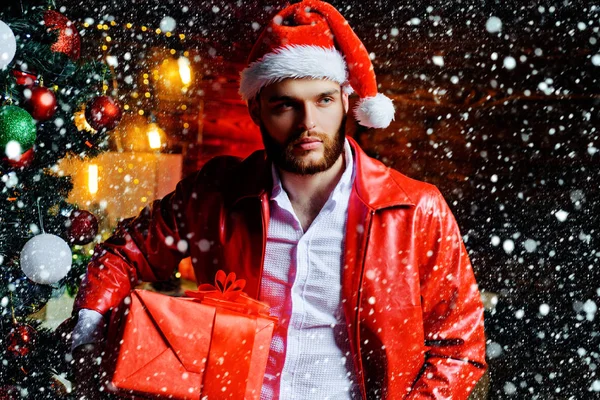 Homem com caixa de presente de Natal. Um homem bonito. Férias de inverno e xmas. Ano Novo na árvore de Natal e guirlanda. Conceito de férias. — Fotografia de Stock