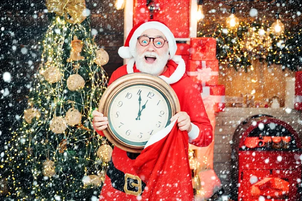 Άγιος Βασίλης κρατώντας ρολόι με αντίστροφη μέτρηση για τα Χριστούγεννα ή το Νέο Έτος Άγιος Βασίλης σε ξύλινο εσωτερικό του σπιτιού δείχνει το χρόνο σε ένα ρολόι. — Φωτογραφία Αρχείου