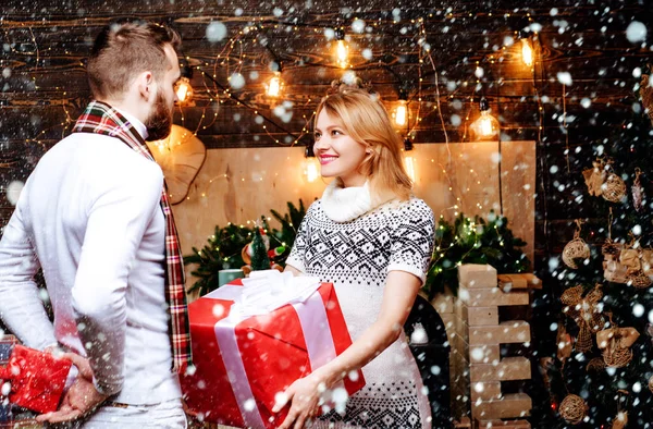 Positive delighted loving couple giving each other Christmas gifts. Celebrating Christmas together. Family winter holidays and people concept. Decorated home. Gift card concept. — Stock Photo, Image