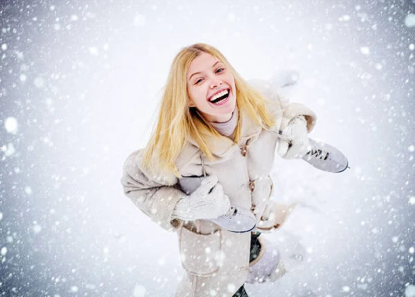 Beautiful girl in the winter outdoors. Beautiful smiling young woman in warm clothing with ice skates. Snowing snow winter concept. — Stock Photo, Image