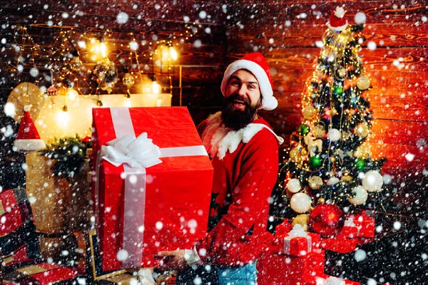 Liefergeschenke. Geschenkemotionen. Hipster mit rotem Weihnachtsmann-Hut und Geschenk. Weihnachtsmann wünscht frohe Weihnachten und ein gutes neues Jahr. — Stockfoto