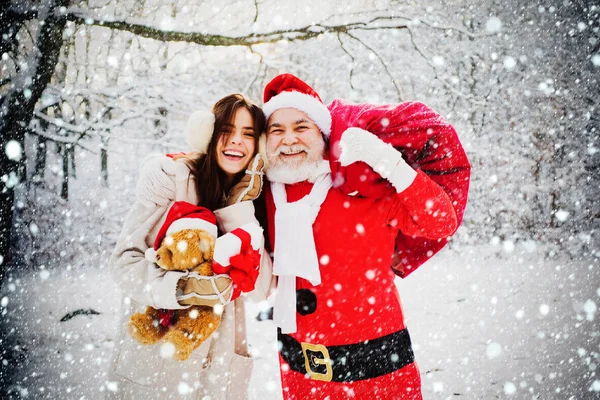 Santa with winter woman in red suit walking along the road to Christmas. Santa Claus and snow woman in red costume walk in winter forest. — Stock Photo, Image