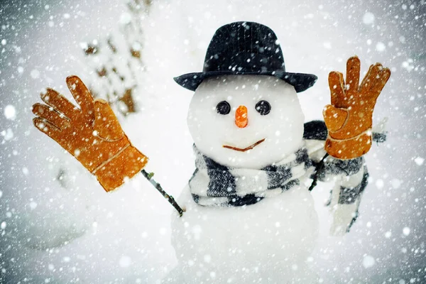 Happy snowman with gift boxes standing in winter Christmas landscape. Winter holidays sale banner. Cute snowman in hat and scarf on snowy field.