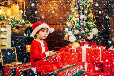 Güzel bebek noel keyfini çıkarın. Noel baba çocuk küçük çocuk evde Noel kutlamak. Aile tatili. Çocuk sevimli çocuk neşeli ruh hali noel ağacı yakınında oyun. Neşeli ve parlak Noeller. Açılış hediyesi