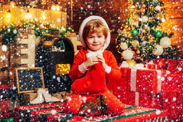 クリスマス・ストッキングオープンエンドのゲーム。暖かい服を着た小さな男の子がテキスタイルのおもちゃで座って遊んでいます。クリスマスの奇跡と新年の気持ち。幼少期の最初の記憶. — ストック写真