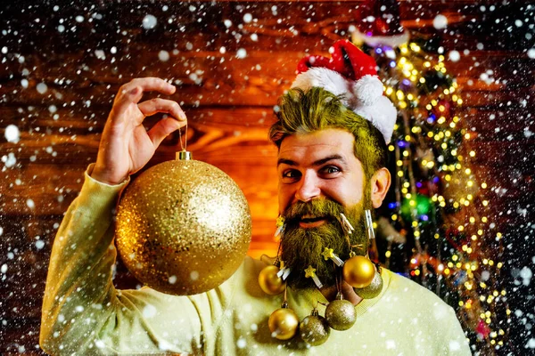 Retrato de Santa hombre divertido en el interior con regalo de Navidad. Feliz invierno. Ambiente navideño casero. Santa posando sobre fondo de madera vintage . —  Fotos de Stock
