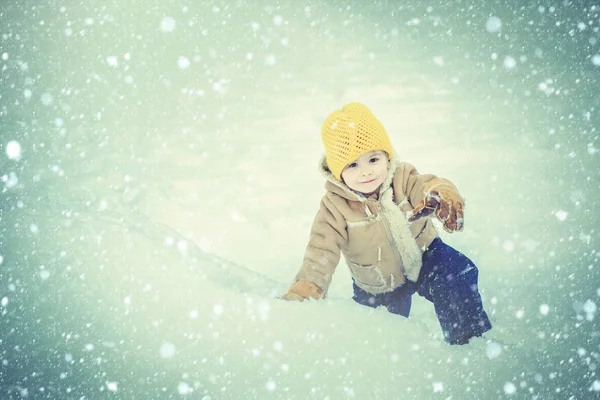 Šťastné dítě se baví na zimním poli se sněhem. Zimní vánoční emoce. Šťastný rozesmátý batole chlapec hrát v zasněženém zimním parku na Štědrý den — Stock fotografie