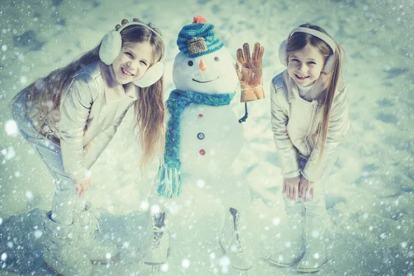 As crianças fazem boneco de neve no fundo branco da neve. Tema Natal feriados inverno ano novo. Inverno neve azul tonificado . — Fotografia de Stock