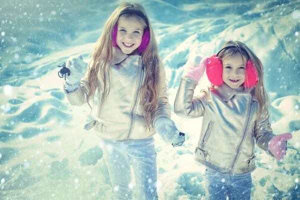 Tema Jul semester vinter nytt år. Porträtt av två små flickor leker med snö på vintern. Barn i Winter Park spelar snöbollar. — Stockfoto