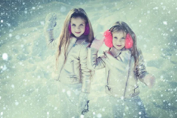 Barn i Winter Park spelar snöbollar. Söta systrar som leker i snö. Vinterkläder för barn och småbarn. Små flickor kastar snöboll i parken. — Stockfoto