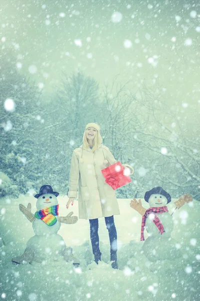 Ung kvinna vinterporträtt. Julvintermänniskor. Vinterporträtt av ung vacker kvinna i snö Trädgård gör snögubbe. Vinter snö blå tonas. — Stockfoto