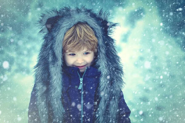 雪の屋外で冬の公園で遊んでかわいい幼児の少年。冬の時間の少年の夢。冬を楽しむのによく服を着た。田舎で冬。雪の青トーン. — ストック写真