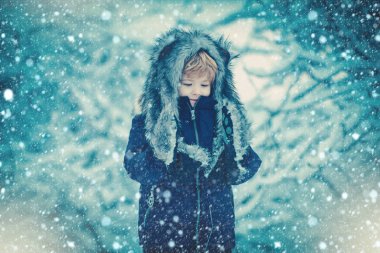 Çocuklar beyaz kar tarlasında karlı ağaçlara karşı eğleniyorlar. Çocukların kış portresi. Çocuk kış ormanındaki karlı tarlada oynuyor.
