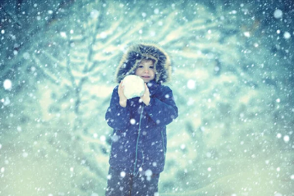 Vinter på landet. En liten pojke som går på vinterfältet. Väl klädd njuter av vintern. Barn vinter porträtt. — Stockfoto