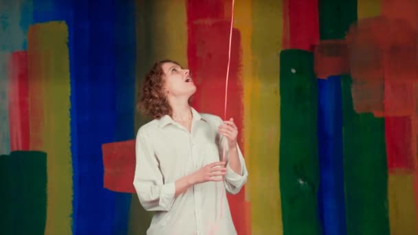 San Valentino Bellezza angelo ragazza con palloncini rossi che ridono arcobaleno colore sullo sfondo. Gioioso angelo femmina divertirsi e festeggiare con palloncino di colore rosso . — Video Stock