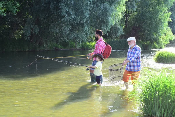 Szczęśliwi ludzie mają wspólne wędkowanie i zabawę. Męskie hobby. Mężczyzna w różnym wieku. Aktywny tryb życia na świeżym powietrzu. Ojciec i syn łowią ryby.. — Zdjęcie stockowe