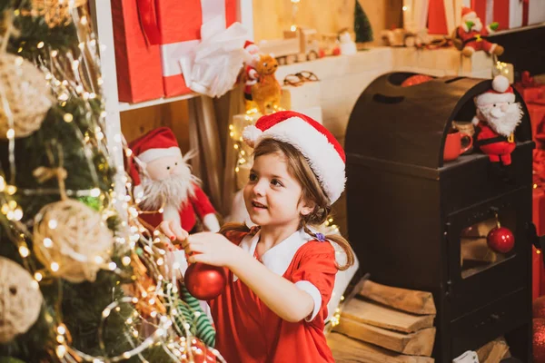 Weihnachtsspielzeug - Mädchen schmückt den Weihnachtsbaum. Weihnachtskind schmückt Weihnachtsbaum mit Christbaumkugel. — Stockfoto