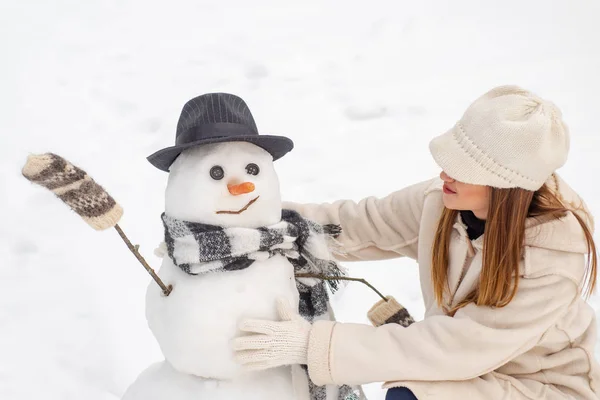 Chica divertida de Santa posando en el clima invernal. Chica jugando con muñeco de nieve en el parque de invierno. Feliz Navidad y Felices Fiestas . — Foto de Stock