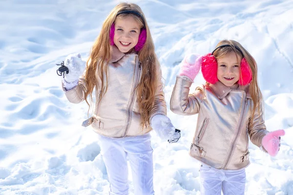 Theme Christmas holidays winter new year. Portrait of two little girls play with snow in winter. Children in Winter Park playing snowballs. — Stock Photo, Image