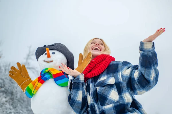 Zimní žena v mrazivém zimním parku. Roztomilá dívka dělá sněhuláka na zasněženém poli venku. Dobře oblečená a užívající si zimu. — Stock fotografie