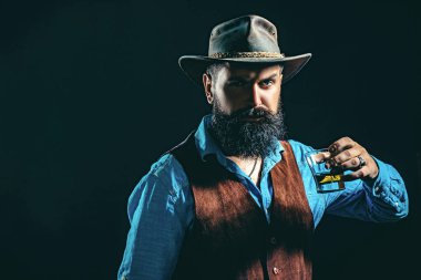 Barmen elinde bir bardak viski tutuyor. Tatma ve degukasyon konsepti. Viski ya da viskili antika bir adam. Barmen deri önlüğü bardakta viski kokteyli tutuyor..