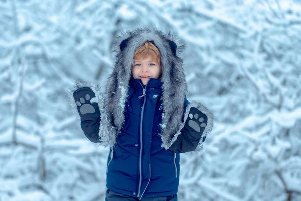 Vinterlandskap av skog och snö med söta barn pojke. Vinterungen poserar och har kul. Söt liten unge njuter i vinterparken i snö. — Stockfoto