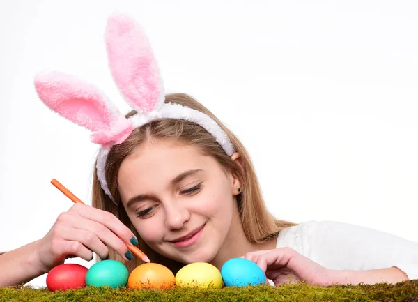 Hagyományos húsvéti ünnepi dekorációk. Boldog húsvéti ünnepeket! Aranyos mosolygós kislány visel nyuszi fülek és díszítő színes húsvéti tojás. — Stock Fotó