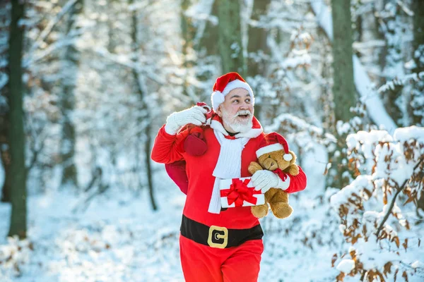 サンタ魔法の霧のフィールドに沿って歩いてください。大きな袋でサンタクロース。クリスマスをお祝いします。サンタクロースは雪に覆われたフィールドで冬に贈り物の袋を持って行く. — ストック写真