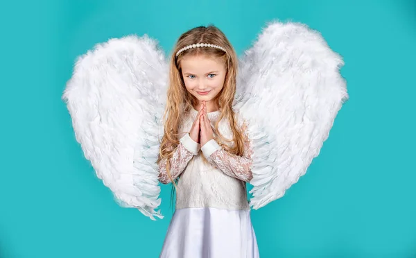 Anak dengan wajah malaikat. Gadis imut berpose dengan sayap malaikat. Gadis malaikat kecil yang cantik berdiri dengan lenganmu di dekat dadamu seperti dalam doa. Malaikat tangan kecil menyeberang untuk Anda . — Stok Foto