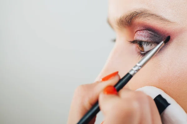 Lyxig makeup av professionell makeup artist i studio. Vogue, kosmetika och glamour koncept. Närbild kvinnor ögon med skimrande lila sotad ögon makeup. — Stockfoto