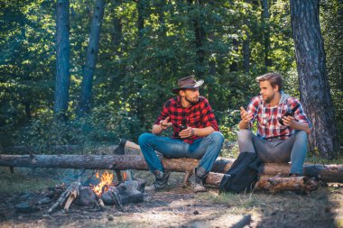 Adam işini yapıyor. Kamp macerası ve seyahat konsepti. Mutlu arkadaşlar doğada şenlik ateşinin keyfini çıkarıyorlar. İki arkadaş hafta sonları piknik ormanlarında piknik yapar. Yaz tatili.