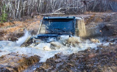 Çamurda iz sürmek. Off-road vagonu. Safari. En iyi off-road araçları. Jip küreğe çarptı ve bir toz püskürtüsü aldı. Dağlar arasında off-road spor aracı.