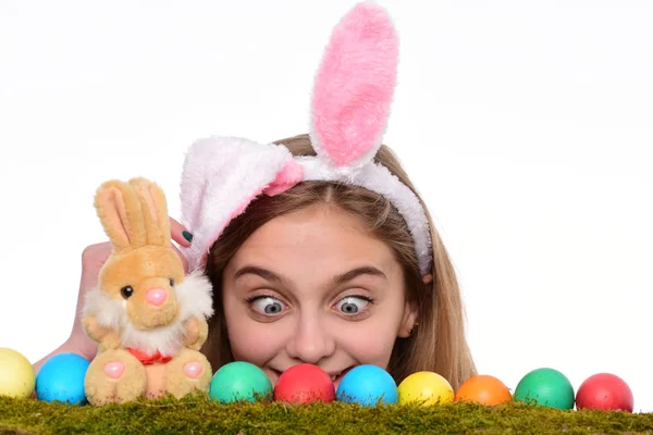 Niña loca vistiendo orejas de conejo y mirando coloridos huevos de Pascua pintados. Decoraciones tradicionales de las fiestas de Pascua. Feliz Pascua concepto de vacaciones . — Foto de Stock