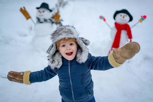 Enjoying nature wintertime. Winter kid. Funny boy posing on winter weather. Snowman and funny little boy kid in the snow. Snowman — Stock Photo, Image