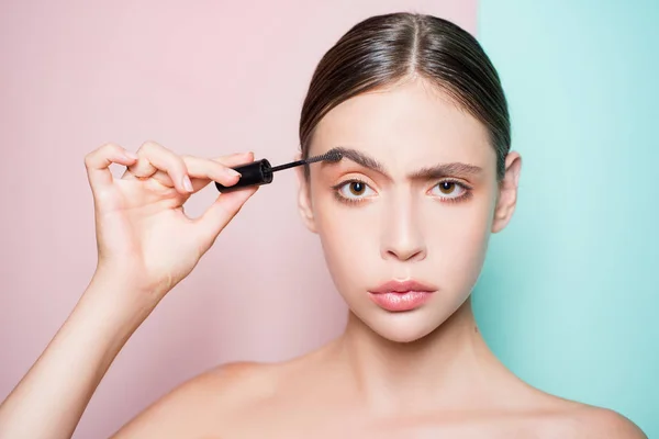 Young beautiful woman does natural brow makeup. Portrait of girl with professional nude makeup and perfect smooth healthy skin. Beautiful girl using brow gel for her brow makeup.