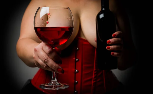 Além disso mulher tamanho com grande mama bonito segurando um copo com vinho e garrafa de vinho. Mulher sexy quente com peitos grandes vestindo espartilho vermelho em estilo vitoriano. Conceito doce de vinho e mulher . — Fotografia de Stock