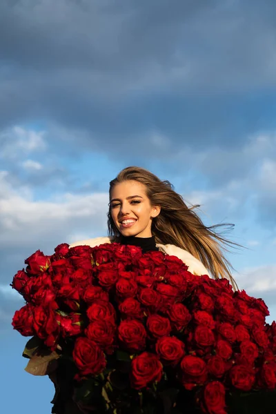 Молодая улыбающаяся девушка наслаждается красными цветами роз. День святого Валентина концепция. Лучшие идеи ко Дню Святого Валентина . — стоковое фото