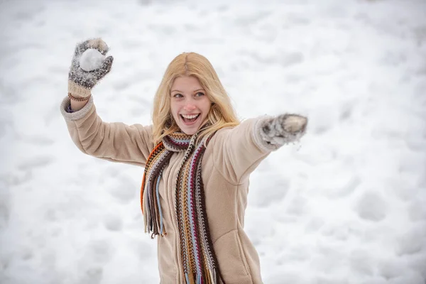 Glad ung flicka som spelar snöbollskrig. Porträtt av en lycklig kvinna på vintern. Glada flicka utomhus. Flicka i vantar håller snöboll. — Stockfoto