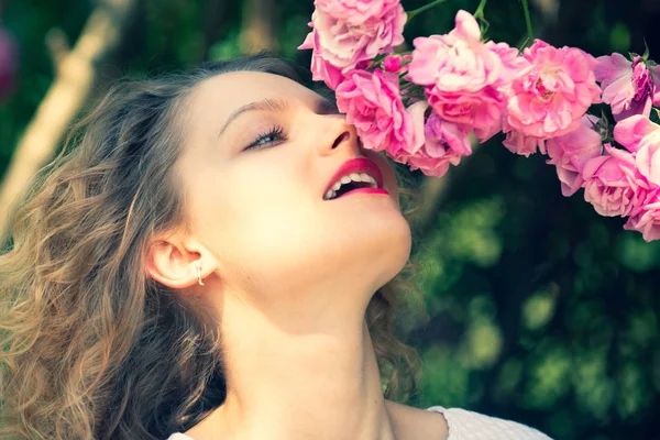 Close up retrato de mulher macia com flor de rosa. Hora de verão. Blossom por aí. Menina bonita cheira a rosa arbusto. Conceito de relaxamento e felicidade. Flores de rosa rosa . — Fotografia de Stock